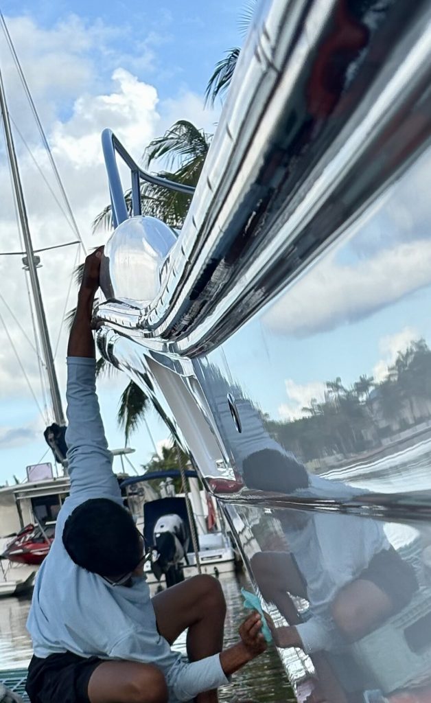 Technician working beside a reflective yacht hull