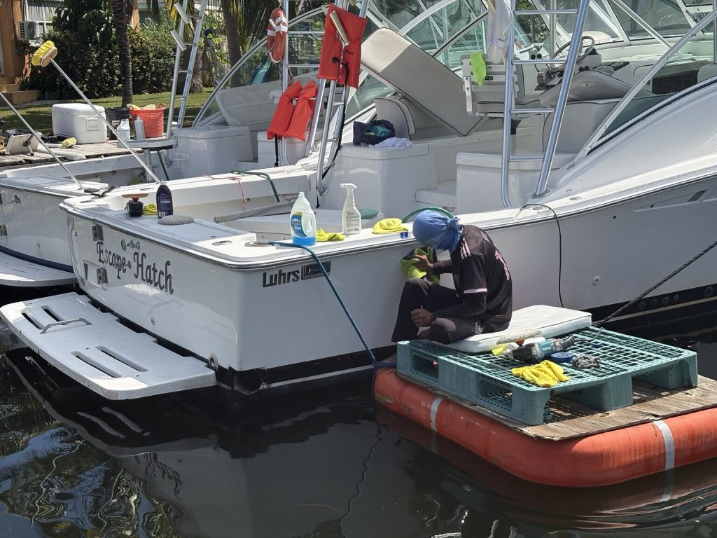 Detailer cleaning the transom of a Luhrs at the dock
