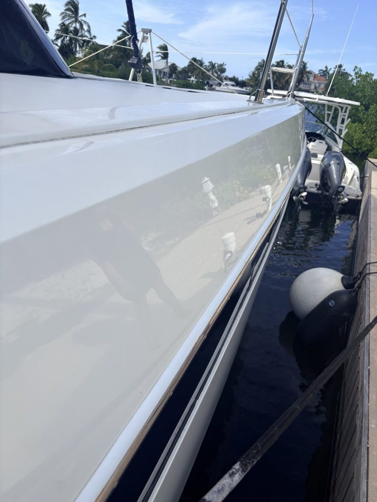 White hull with a blue accent stripe beside a marina