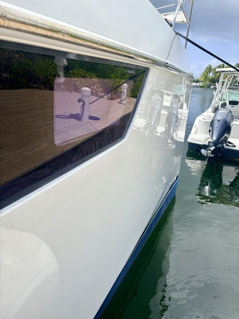 White yacht hull and dark window beside the dock